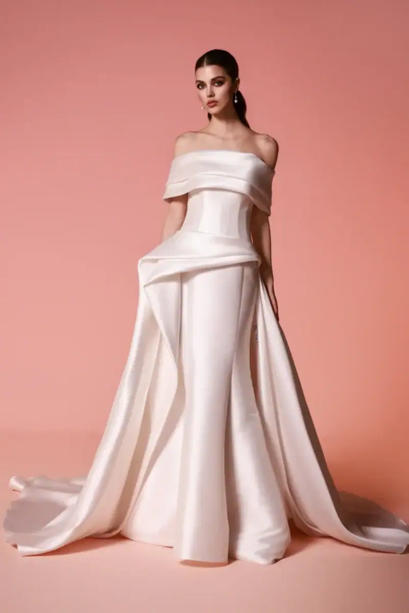 full front of dany tabet evira ivory sheath wedding dress with an off the shoulder neckline and draped skirt detail