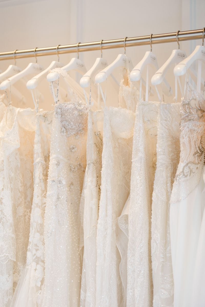 close up of a wedding dress rack that contains floral and sparkle wedding dresses on white hangers