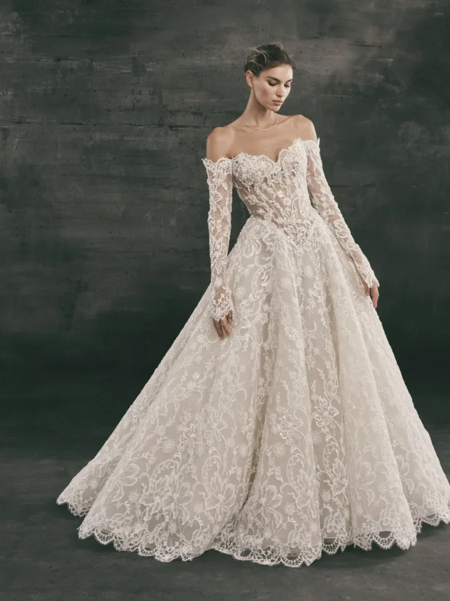 full front of nicole and felicia nf168 ivory lace ball gown wedding dress with a basque waist and off the shoulder long sleeve neckline