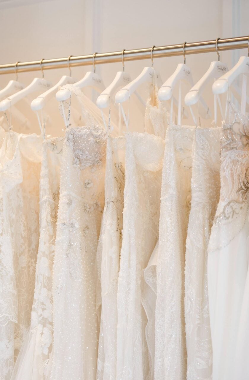close up of a wedding dress rack that contains floral and sparkle wedding dresses on white hangers